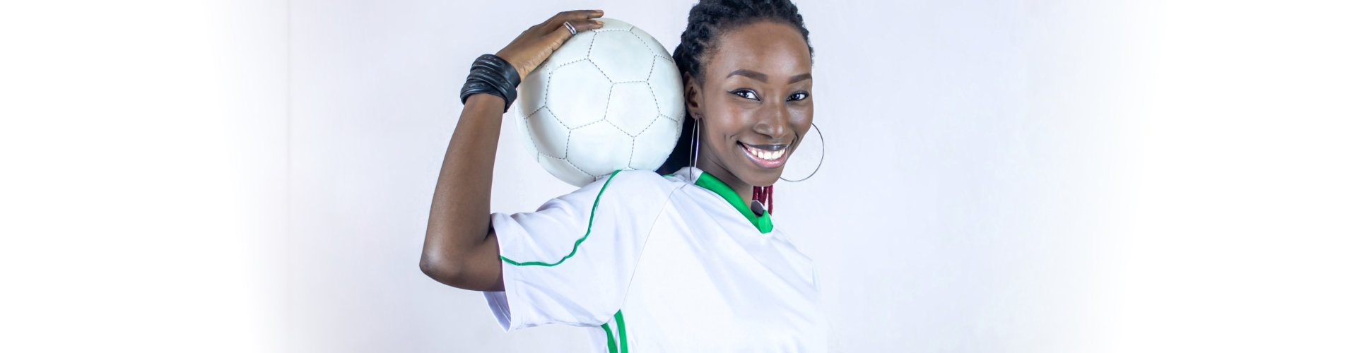 young african soccer player holding his ball on his shoulder smiling